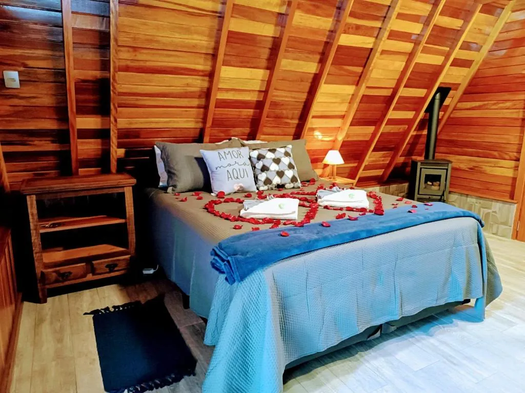 Cama decorada com pétalas de rosa e lareira ao fundo