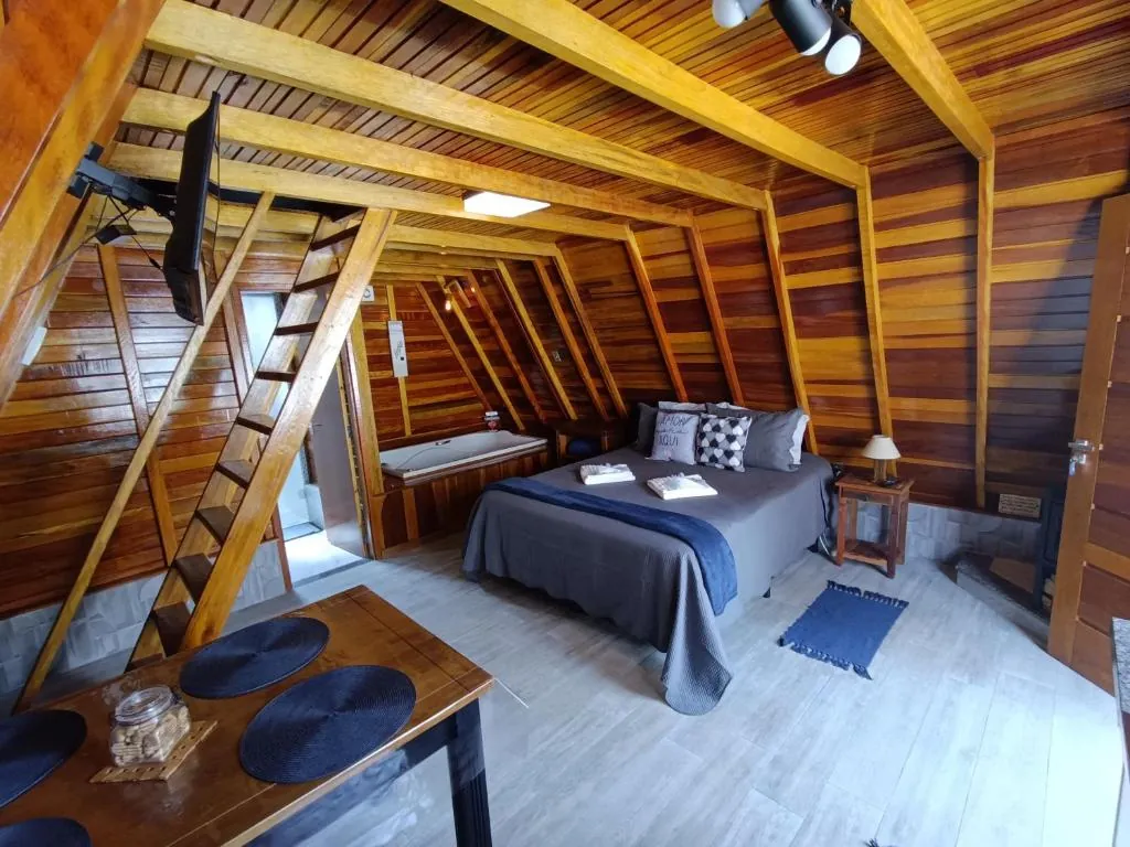 Interior do Chalé Família Rigolo com cama, hidromassagem e escada